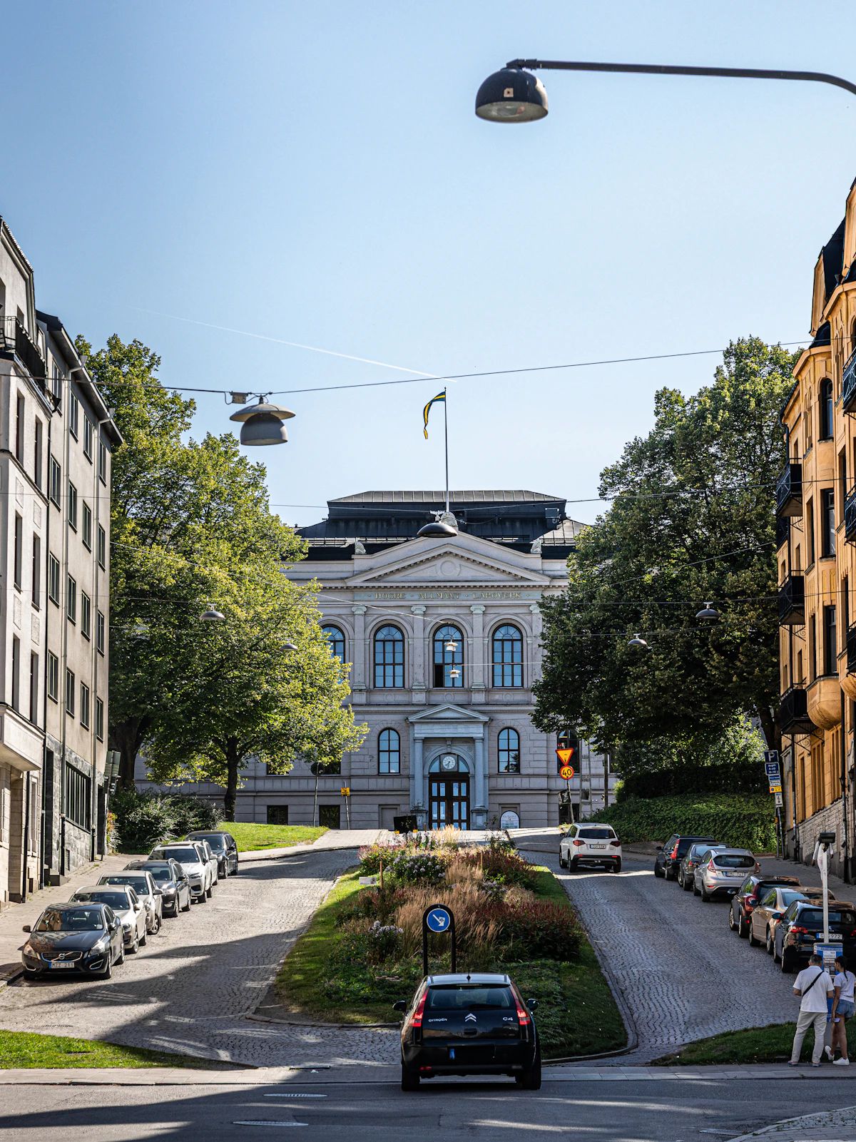 Gata i Norrköping som leder upp mot en klassicistisk byggnad omgiven av träd.