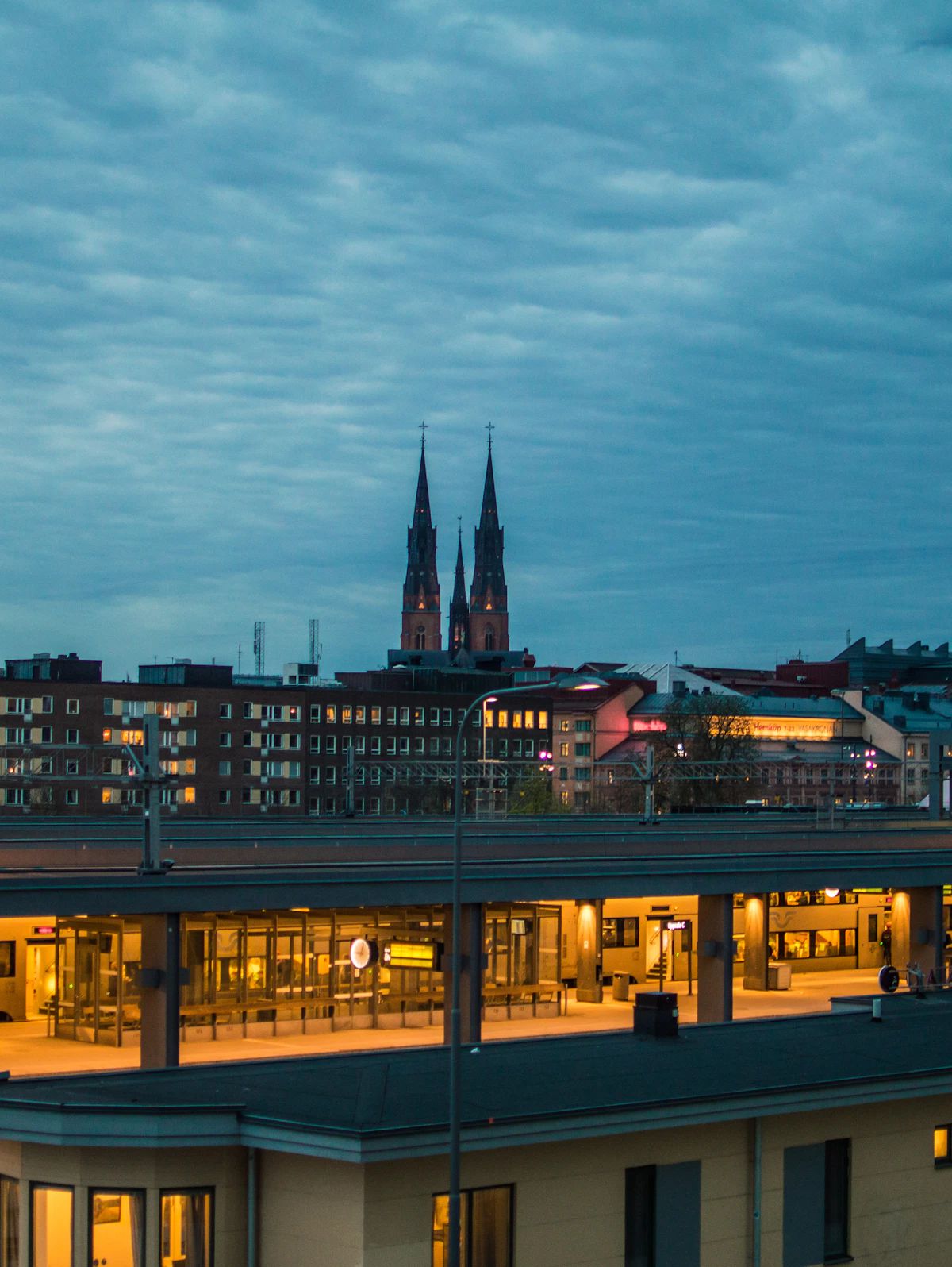 Uppsala domkyrkas torn över stadens tak i skymning, sett från centralstationen.