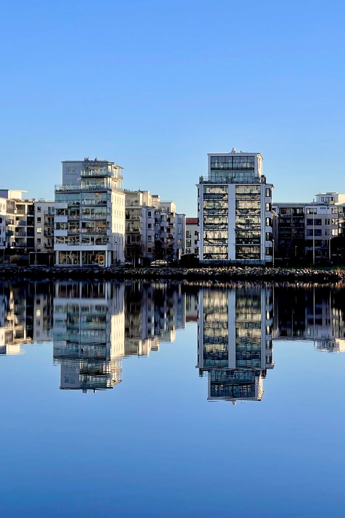 Modern apartment buildings by Lake Munksjön in Jönköping reflected in still water.