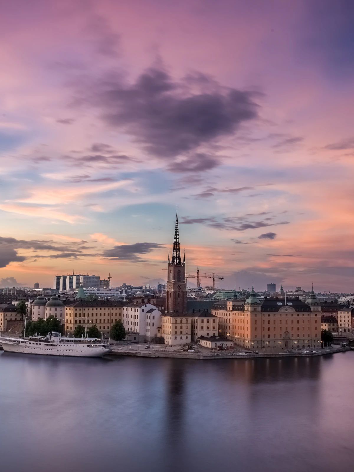 The spire of Riddarholmen Church above the Stockholm skyline at dusk.